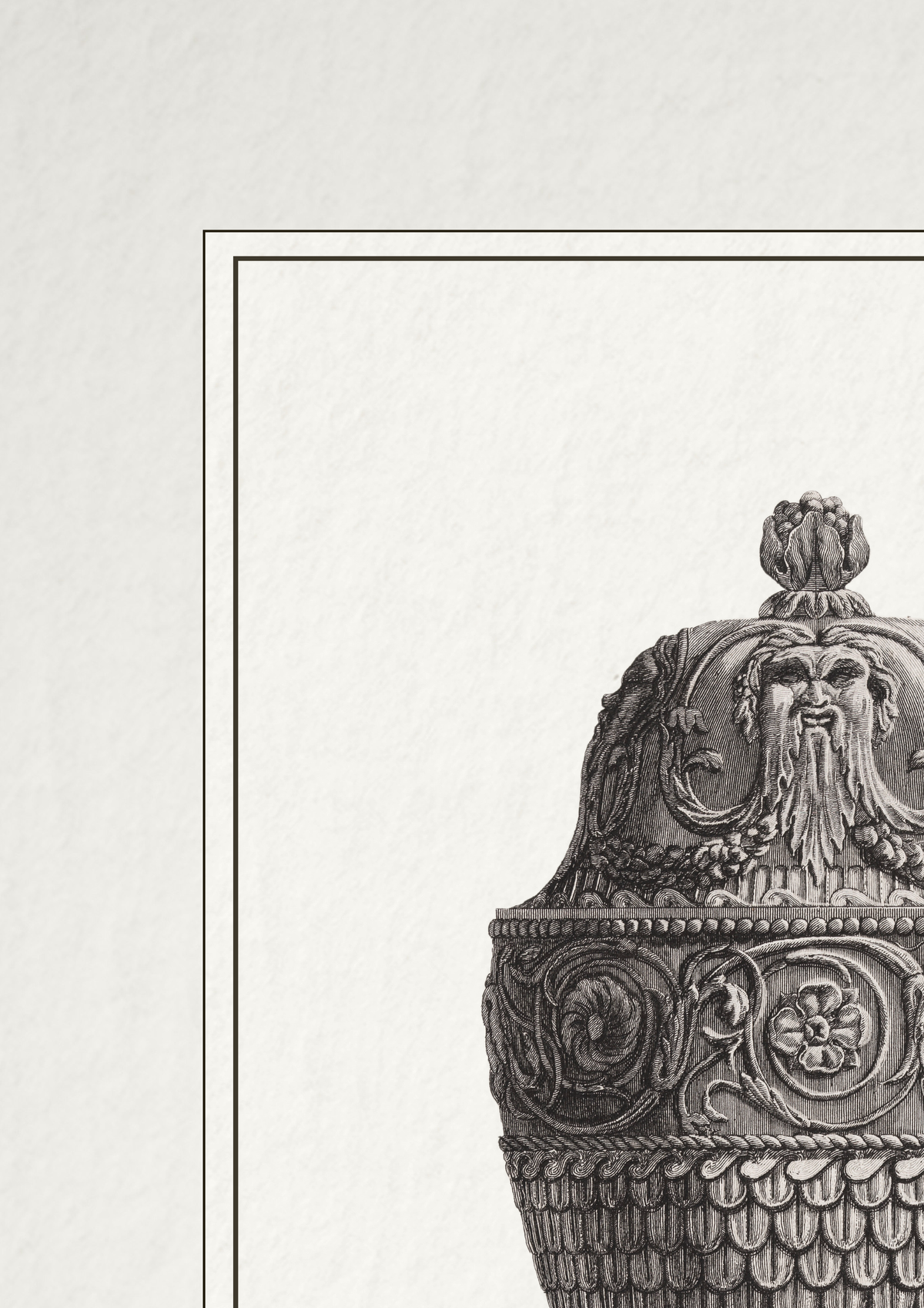 A close-up of an ornate carved decorative object, likely a ceramic or metal vessel with a lid, shown in grayscale on a light textured background with a thin rectangular border.