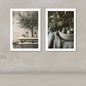 Two framed art prints with white borders displayed side-by-side on a textured beige wall. The left print shows an olive tree on a bench with lanterns, and the right print shows green olives in a bowl with olive branches.