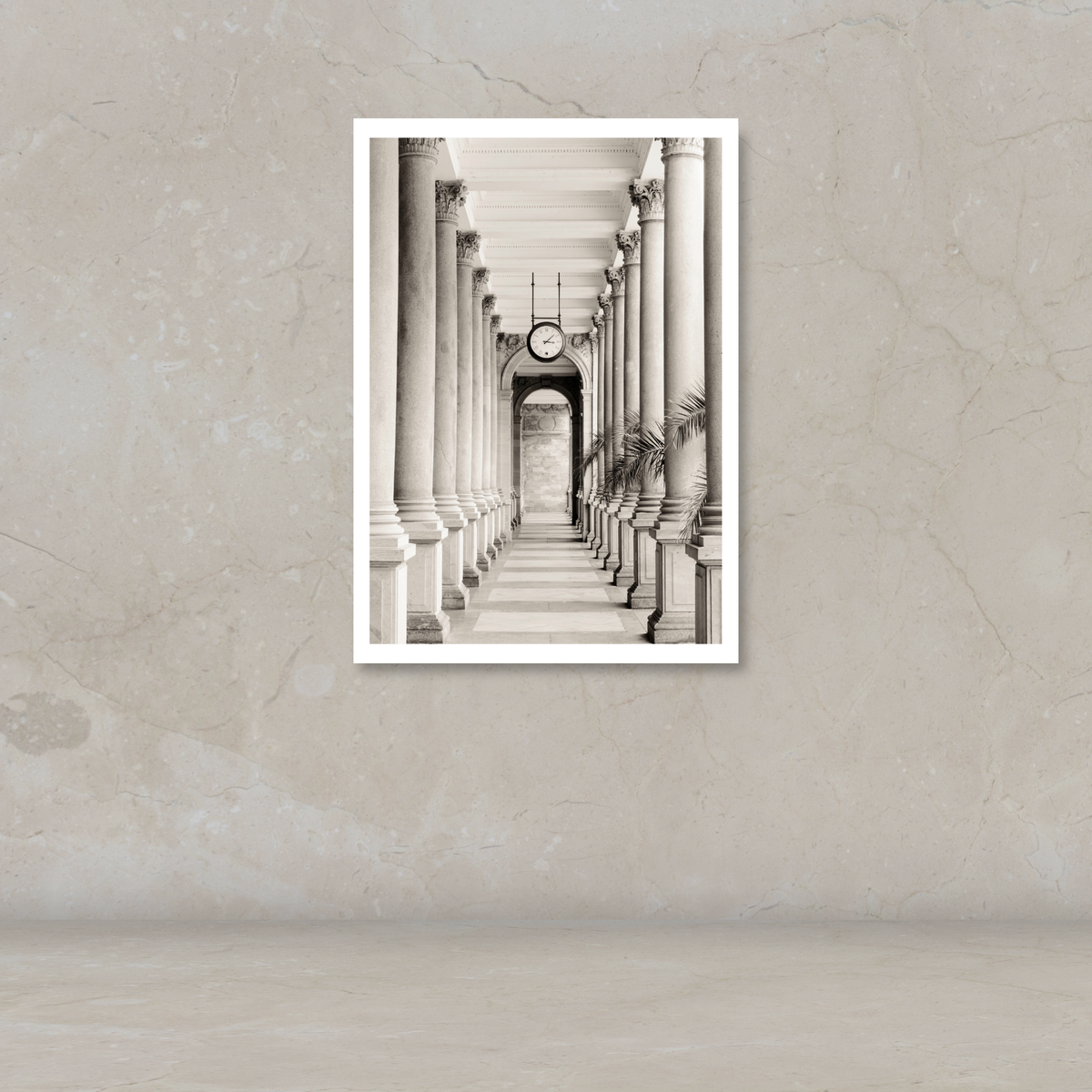 A black and white art print of a classical colonnade with a clock, displayed on a textured beige wall.