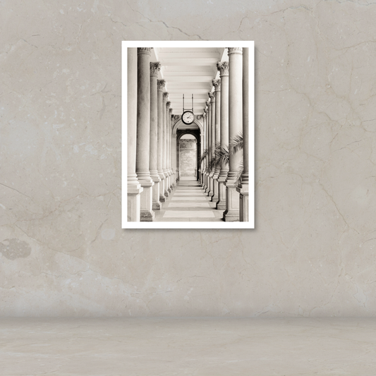 A black and white art print of a classical colonnade with a clock, displayed on a textured beige wall.